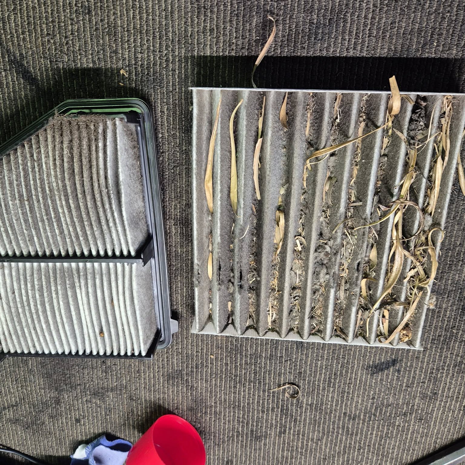 Two heavily soiled filters laid out on the workshop floor