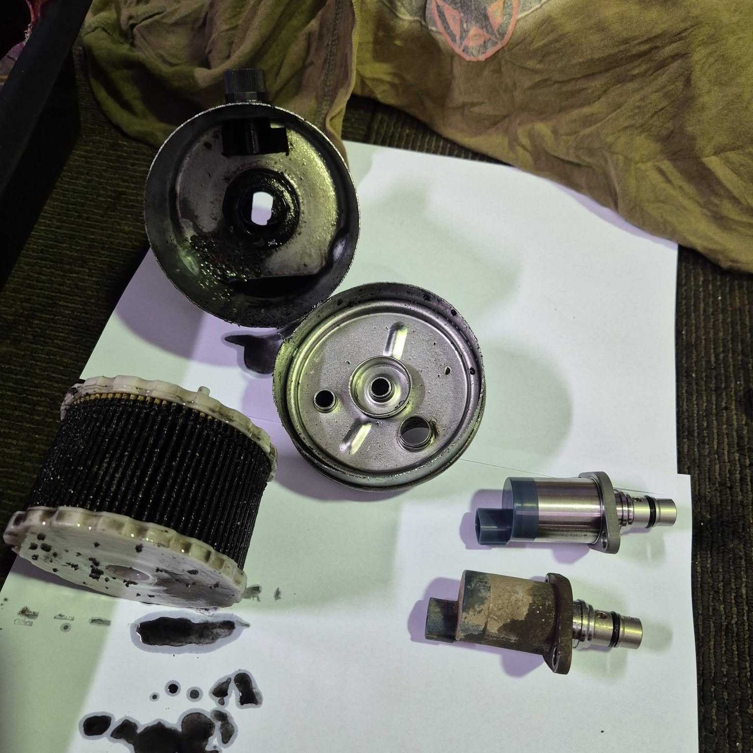A dismantled filter housing and two suction control valves laid out for comparison